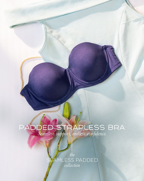 A high-end flat lay composition of a navy blue strapless bra placed over a soft blue dress, accented with floral elements.